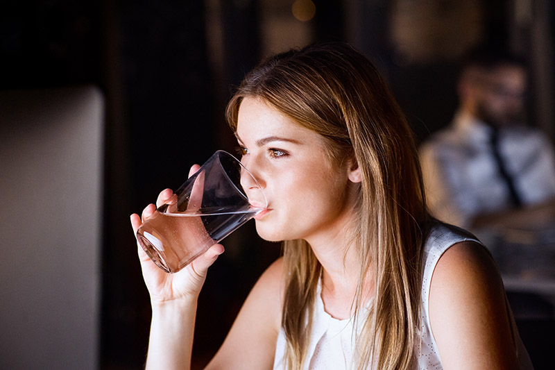 Businesswoman drinking water in office at night.
